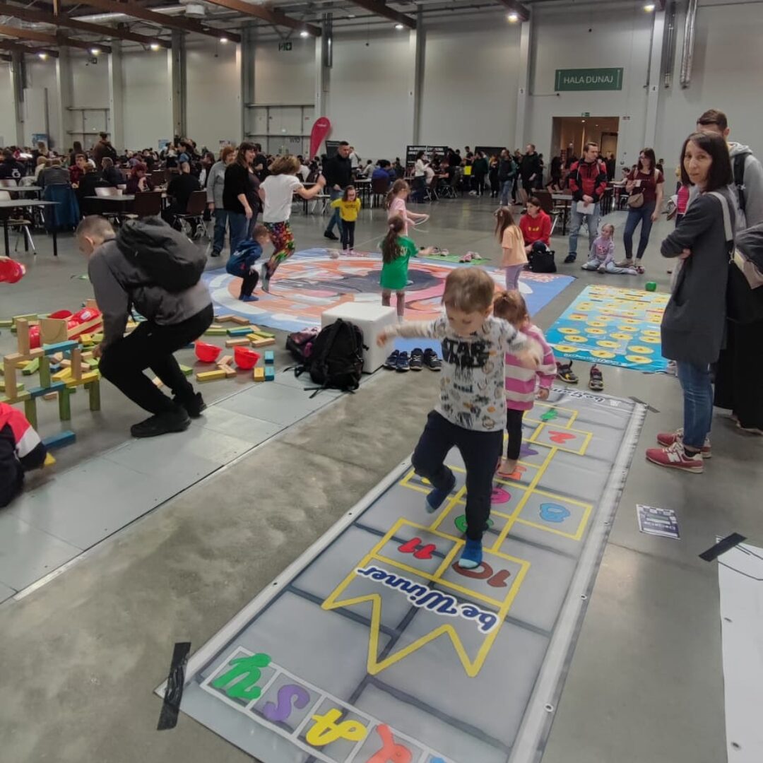 Gra korytarzowa „Klasy” z kolorowymi numerami – dzieci skaczą po polach, rozwijając sprawność i równowagę.