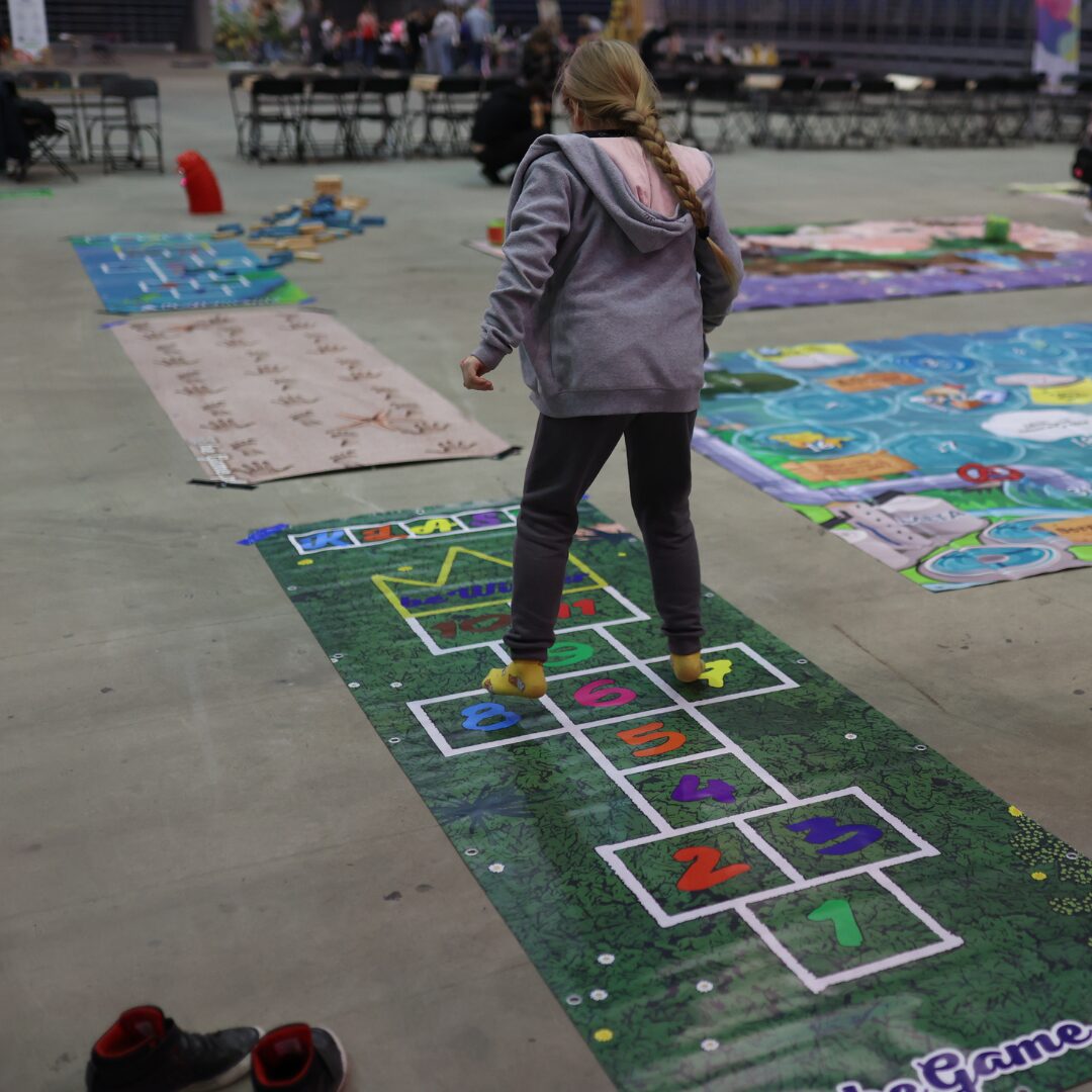 Gra korytarzowa „Klasy” z kolorowymi numerami – dzieci skaczą po polach, rozwijając sprawność i równowagę.